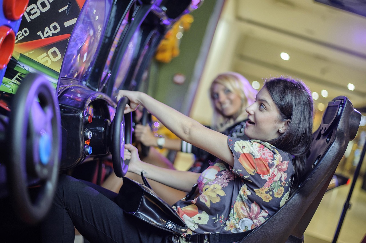 Two kids racing side by side on simulator seats at an event.